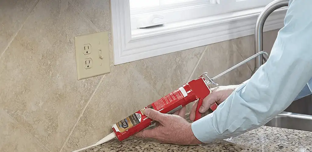 Handyman applying caulk along a kitchen backsplash and countertop seam in Arlington, TX