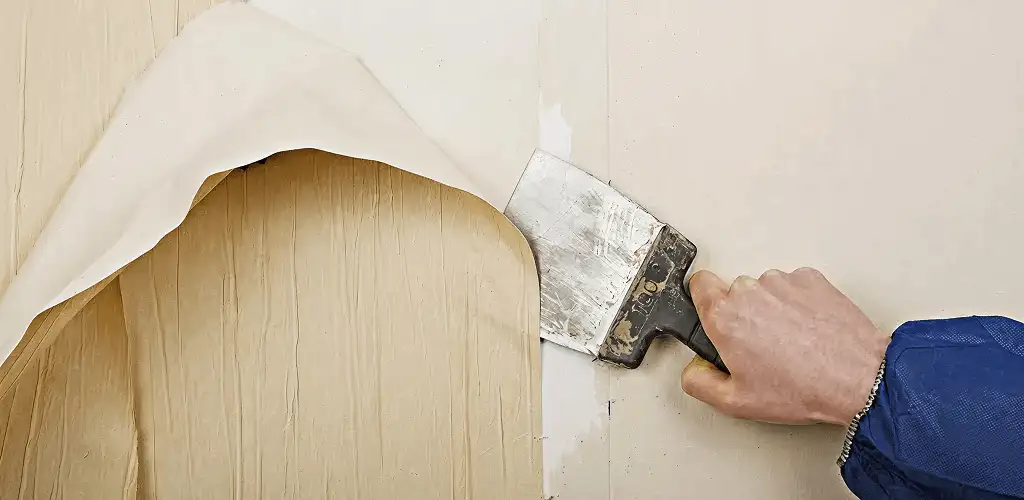 Handyman removing wallpaper with a scraper for wall preparation in Arlington, TX