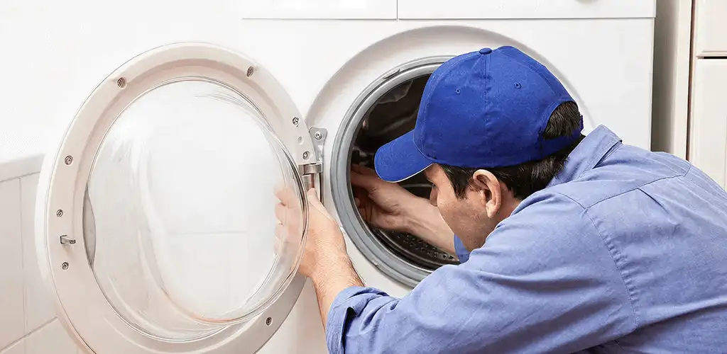 Washing machine repair handyman inspecting a front-load washer drum in Arlington, TX