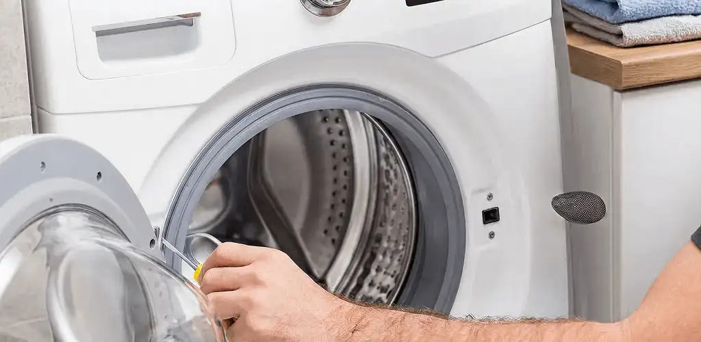 Handyman repairing a front-load washing machine and inspecting the drum in Arlington, TX