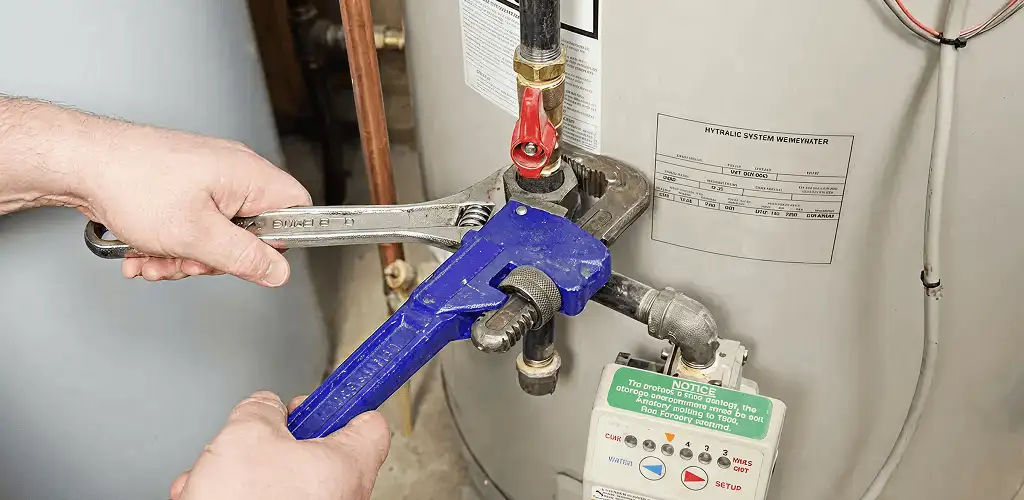Water heater repair technician tightening the shutoff valve and supply line in Arlington, TX